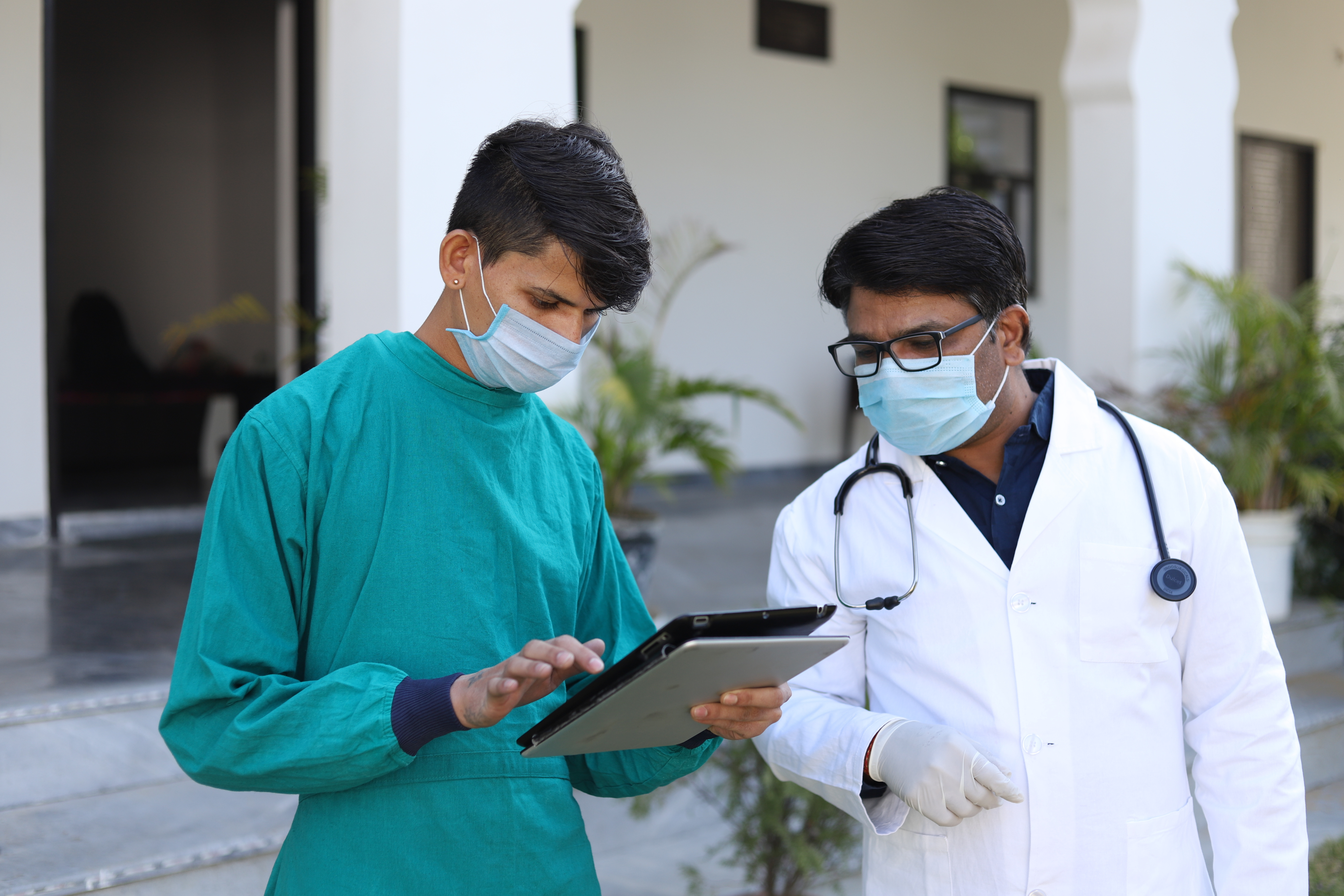 Two doctors in masks looking at a tablet